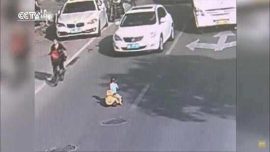Niño esquiva el tráfico montado en un carro de juguete
